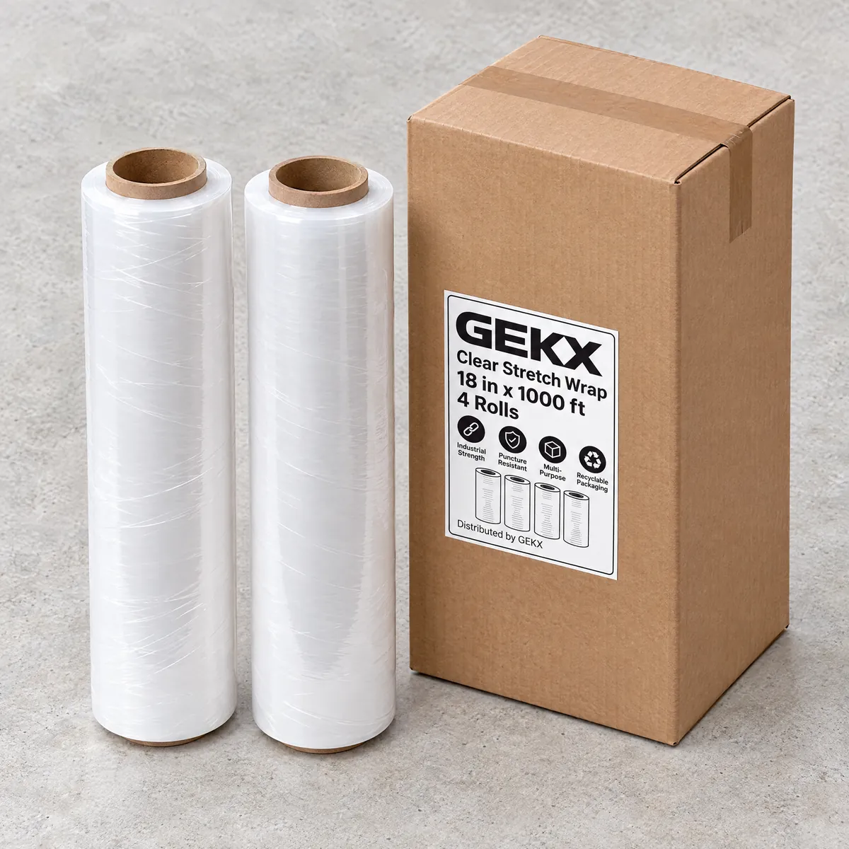 Two GEKX clear stretch wrap rolls standing next to a closed GEKX shipping box on light concrete